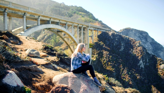 Woman sitting below Bixby Bridge in Big Sur