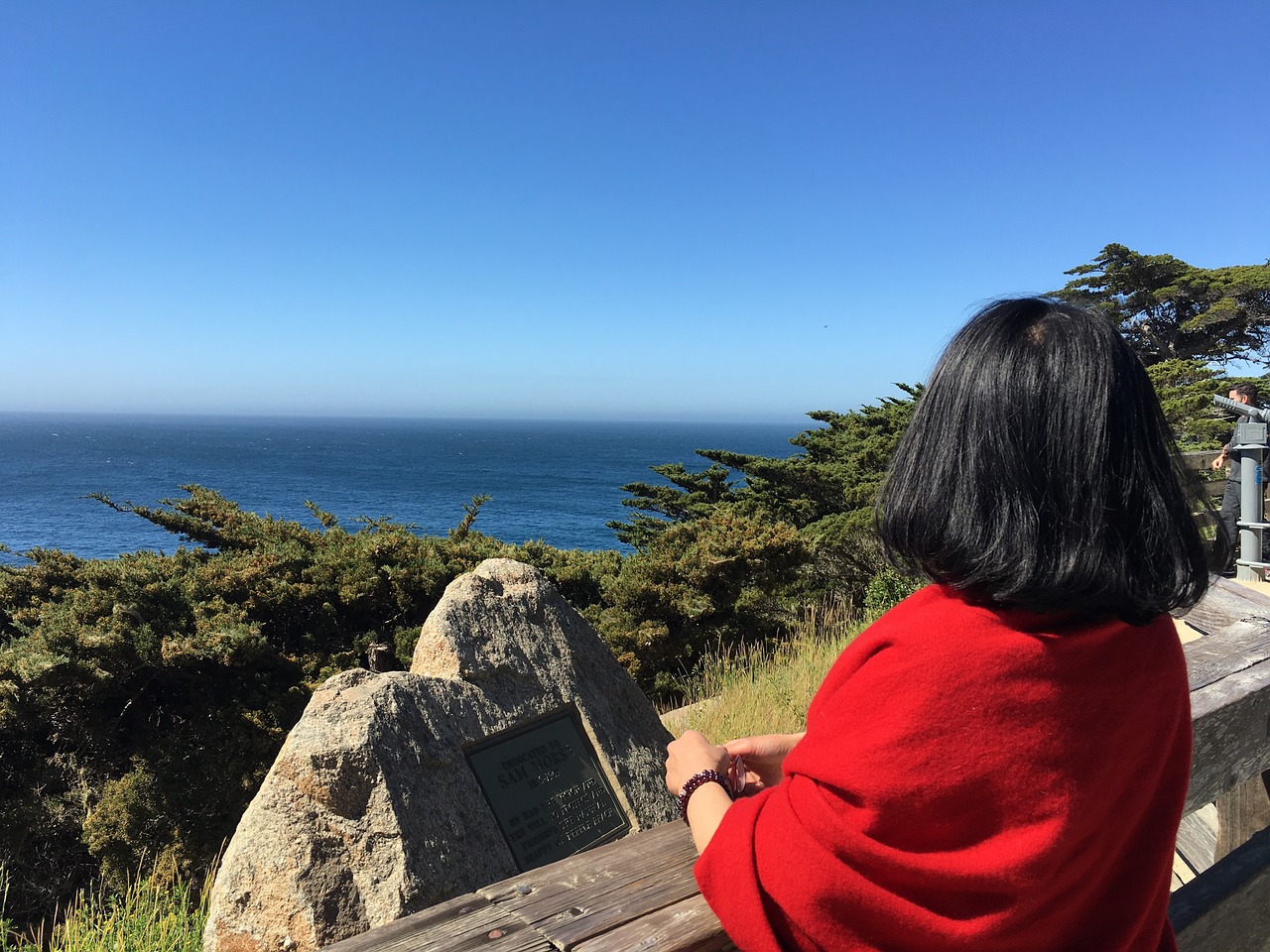 Woman stopped on the Pacific Coast Highway and looking at the Big Sur coastline