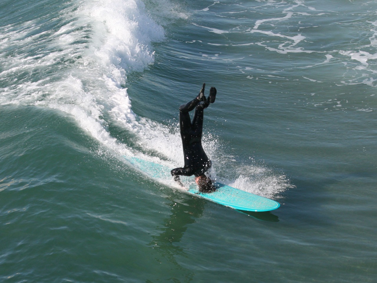 Guy surfing on his head in Huntington Beach, California's Surf City